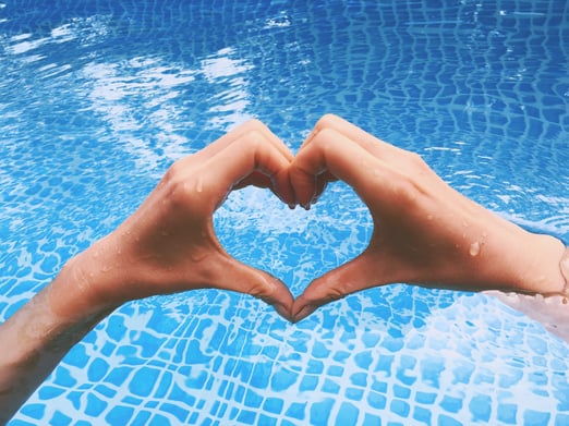 Hands making a heart over a pool