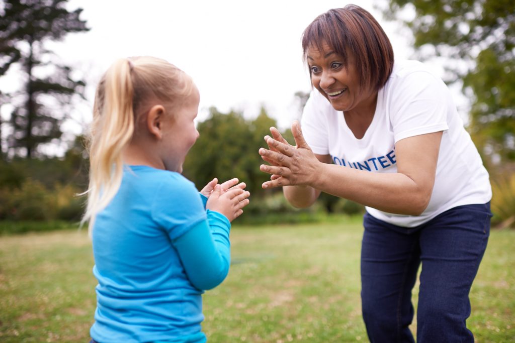 Volunteer clapping with young girl